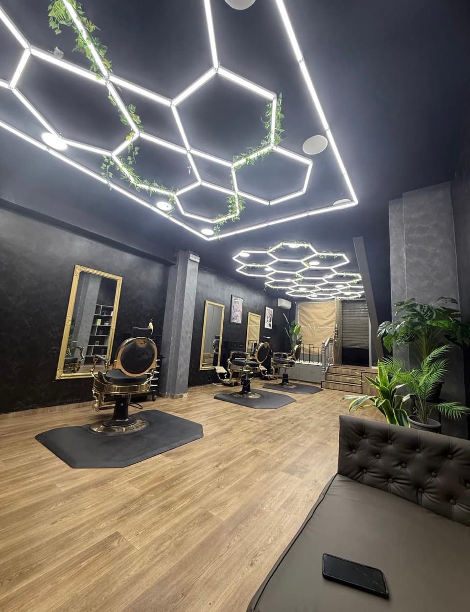 Interior de HB Barbers en Tarragona con sillones de barbero clásicos, espejos con marco dorado e iluminación cálida