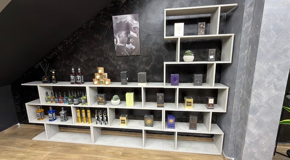 Estantería de productos y colonias de barbería organizada con cuidado en HB Barbers