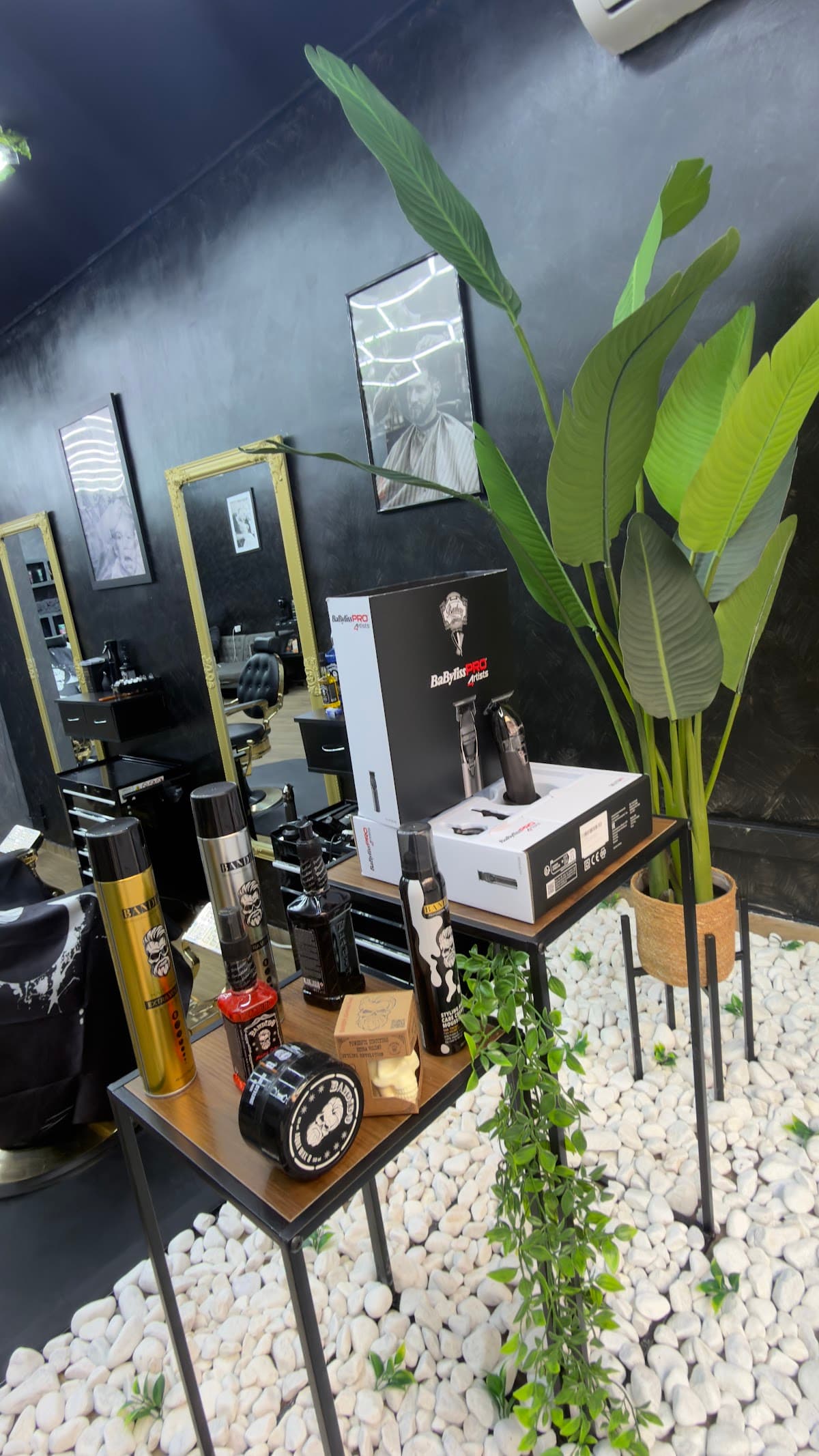 Máquinas de corte profesionales y productos de peluquería sobre una mesa auxiliar en HB Barbers