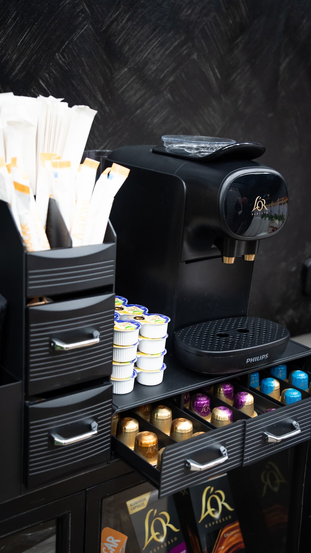 Rincón de café con cápsulas y accesorios para clientes en HB Barbers