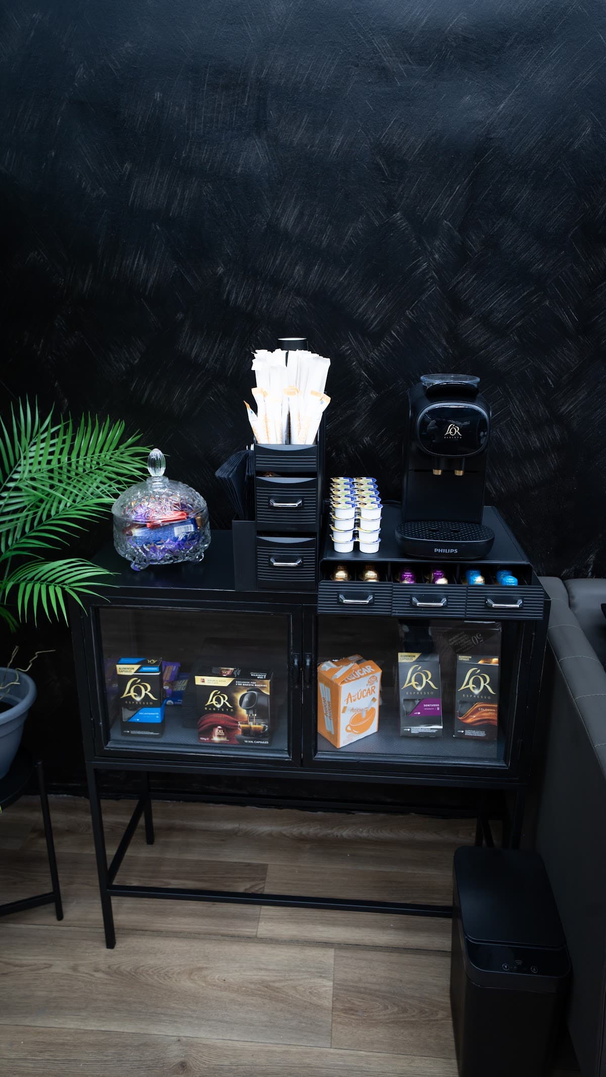 Zona de cortesía con cápsulas de café organizadas en cajones en HB Barbers